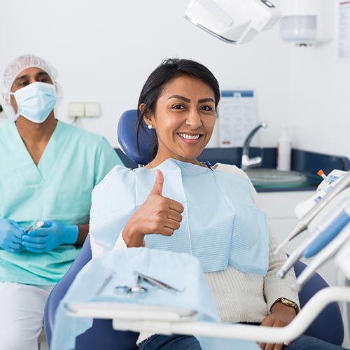 woman giving two thumbs up in dental chair